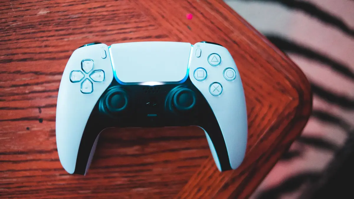 Manette DualSense sur une table en bois : exclusivités PlayStation et portages PC